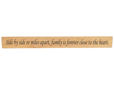 90cm x 10cm, Solid wood decorative home sign, handmade in the UK by Austin Sloan with a loving family quote "Side by side miles apart, family is forever close to the heart." Natural wood with black wording