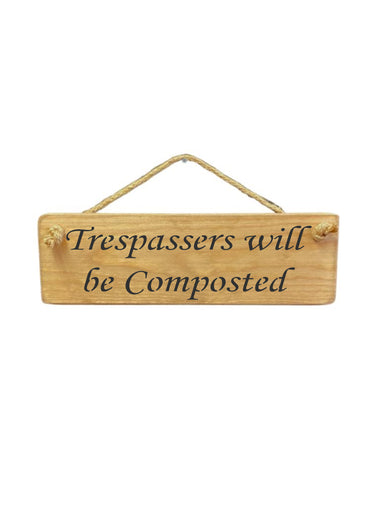 30cm x 10cm, solid wood decorative garden sign, handmade in the UK by Austin Sloan with a humorous quote "Trespassers will be Composted" in a natural wood colour