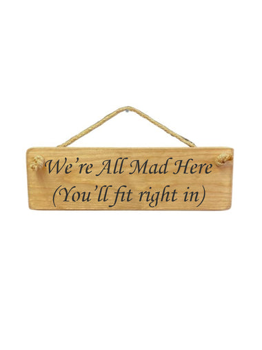 30cm x 10cm, solid wood decorative home sign, handmade in the UK by Austin Sloan with a humorous family quote "We're All Mad Here (You'll fit right in) in a natural wood colour