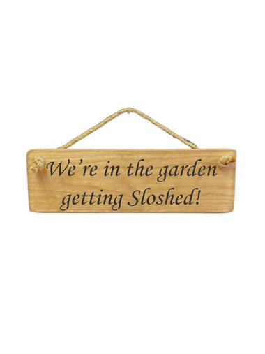 30cm x 10cm, Solid wood decorative garden sign, handmade in the UK by Austin Sloan with a humorous alcohol lovers quote "We're in the garden getting Sloshed!" in a natural wood colour