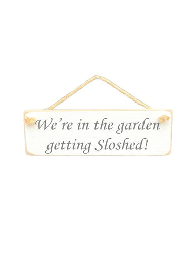 30cm x 10cm, Solid wood decorative garden sign, handmade in the UK by Austin Sloan with a humorous alcohol lovers quote "We're in the garden getting Sloshed!" in a antique white colourr