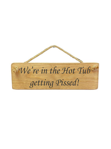 30cm x 10cm, Solid wood decorative hot tub sign, handmade in the UK by Austin Sloan with a humorous alcohol lovers quote "We're in the Hot Tub getting Pissed!" in a natural wood colour