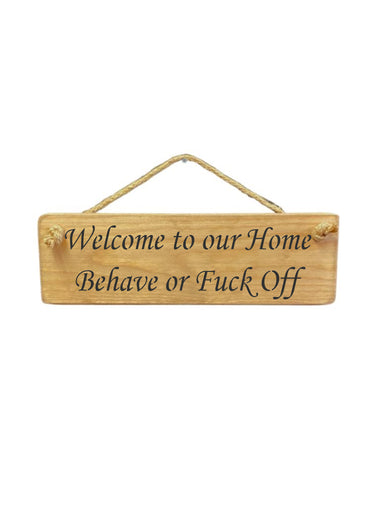 30cm x 10cm, Solid wood decorative home sign, handmade in the UK by Austin Sloan with a humorous quote "Welcome to our Home Behave or Fuck Off" in a natural wood colour